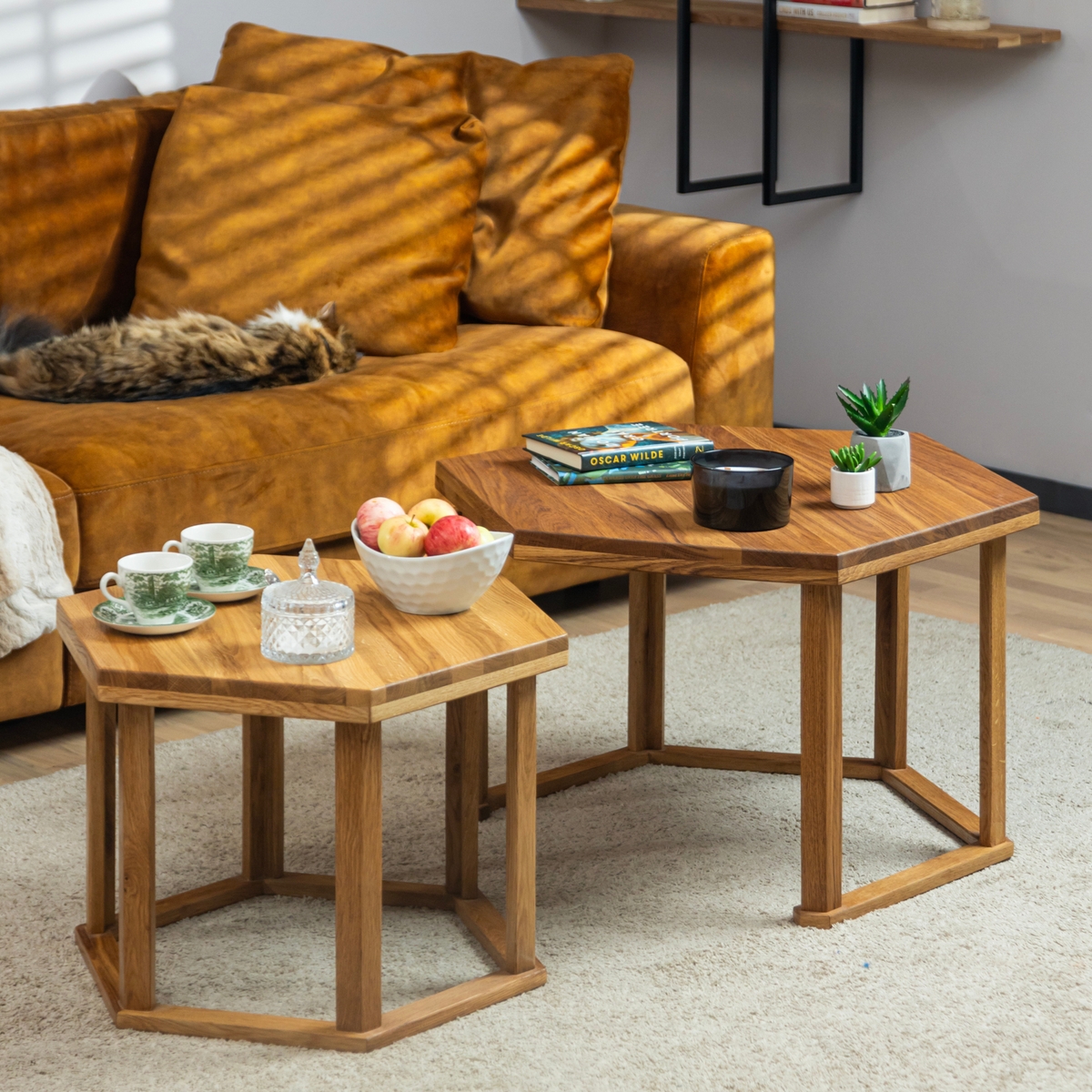 The HEX coffee table styled with books, tea and a candle for  a cozy setting. A cat is sleeping in the background on the couch.