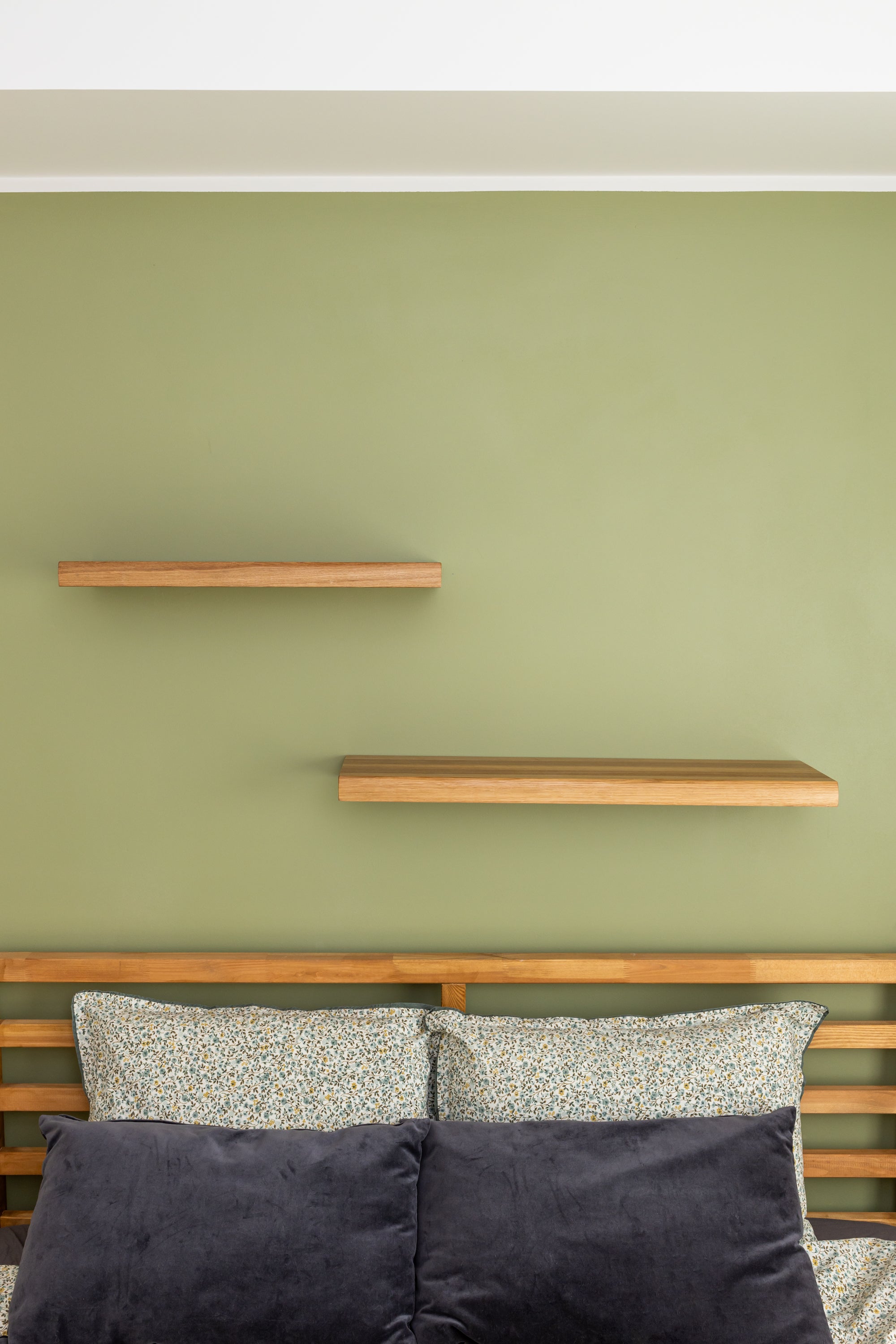 View from the front of the wooden floating shelves TUUL on a green bedroom wall