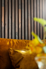 A close up shot of dark decorative wall panels behind a yellow couch