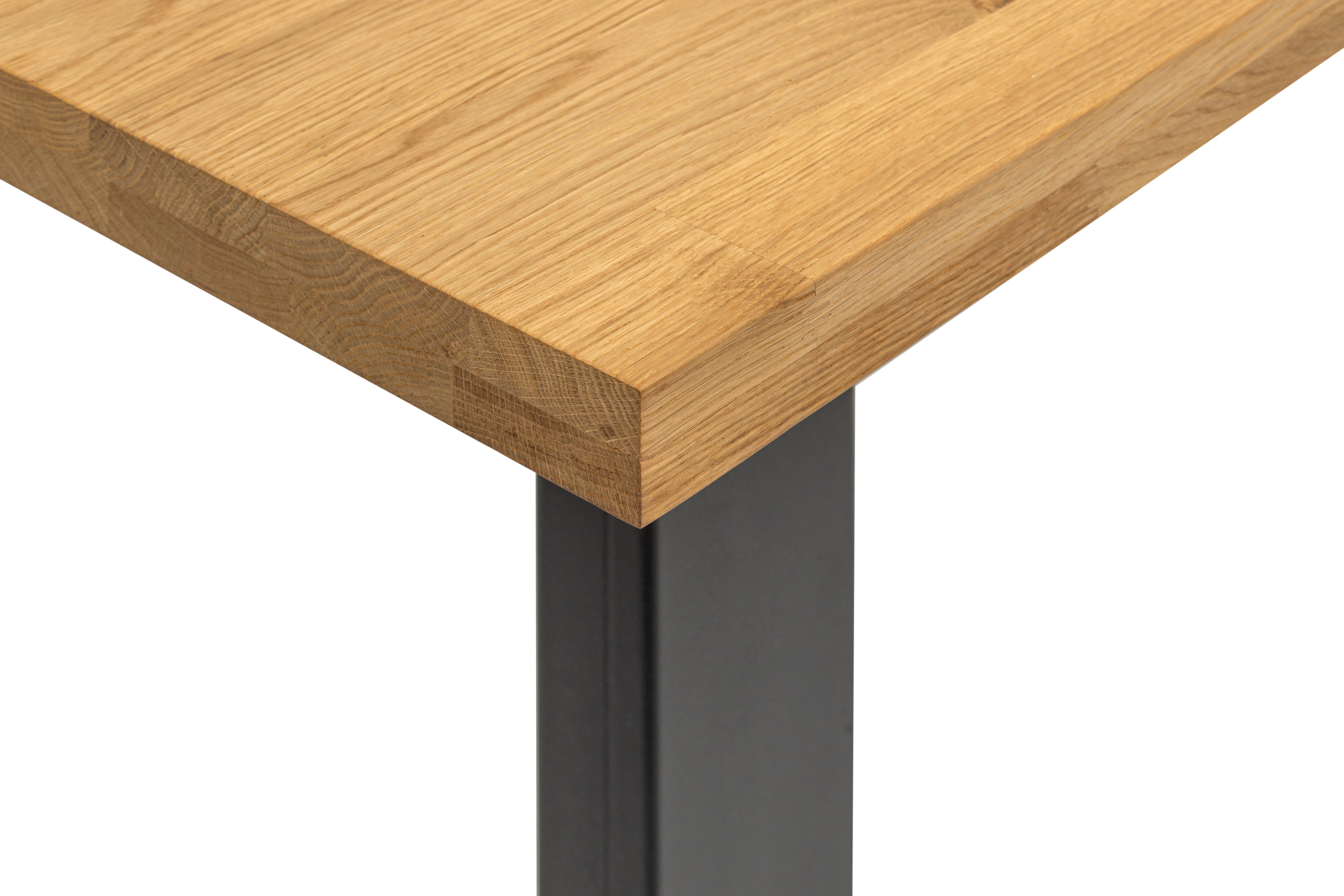 A close up shot featuring the corner of the solid wood dining table liiv and black metal leg