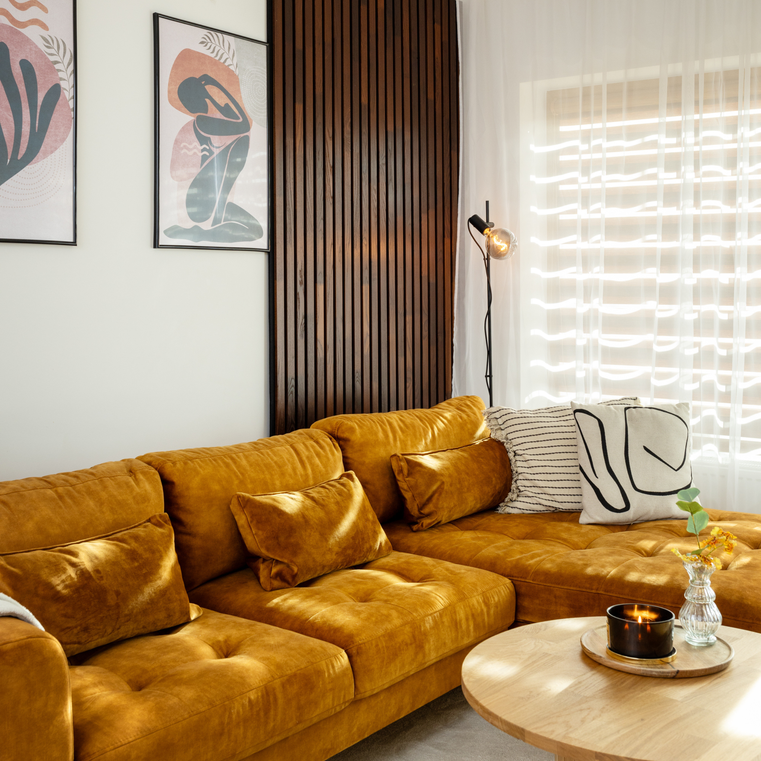 Natural termoash solid wood acoustic panels on a modern and cosy living room wall with a yellow couch and solid wood coffee table 