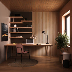 A warm and natural toned home office with natural oak acoustic wall panels on the wall together with wooden mounted shelves. A wooden desk in the front with office equipment and a pink chair with black metallic legs in front of it.