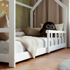 Side view of the White Montessori House bed with barriers in a modern kid bedroom decorated with pillows, toys and fairy lights