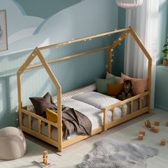 Solid wood Montessori House bed with barriers in a modern kid bedroom decorated with pillows, toys and fairy lights