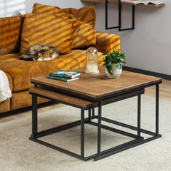 The Nurmenukk coffee table set stacked onto each other and styled with books and a flower for a cozy living room setting