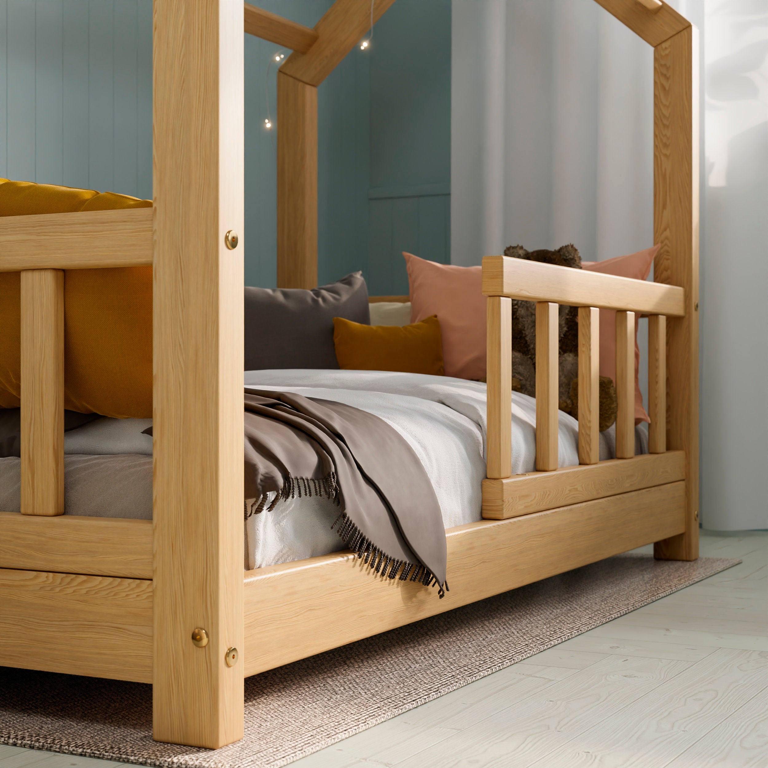 Close up with of the natural wooden housebed ÖÖBIK showcasing the grain of the wood in a modern kids room decorated with pillows and toys