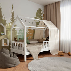 Lit d'enfant en bois blanc ÖÖBIK avec barrières dans une chambre d'enfant moderne et lumineuse décorée de coussins et de jouets.