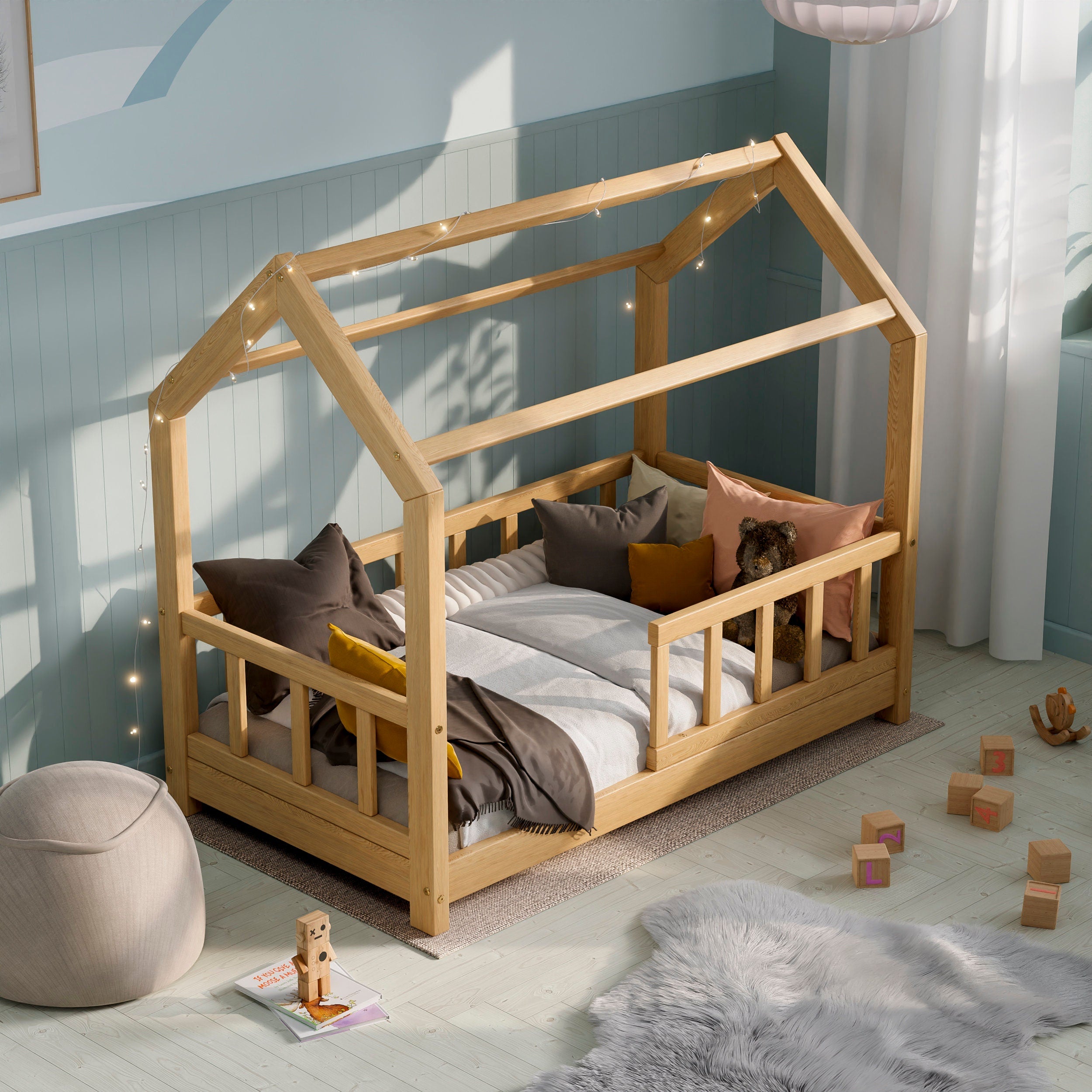 Naturholzhausbett ÖÖBIK in einem modernen Kinderzimmer mit Kissen und Spielzeug dekoriert